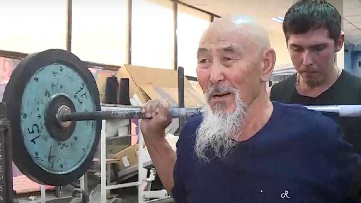    Пожилой мужчина занимается в спортзале с тренером:YouTube/Телеканал Хабар 24