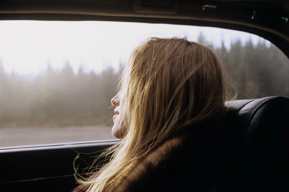 Русые волосы у девушек. Девушка смотрит в окно машины. Светлая девушка. Грустная блондинка. Будет просто не реально