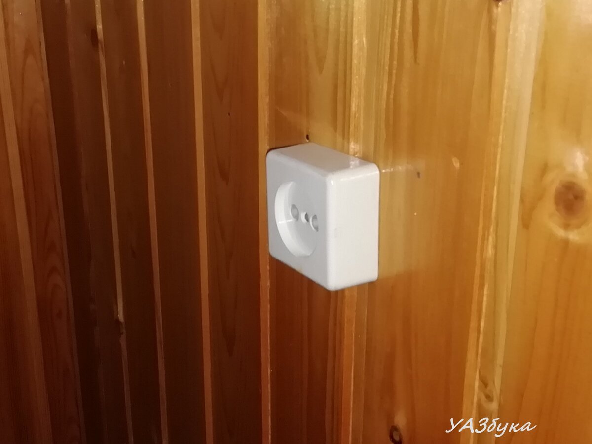 Розетка "из ниоткуда". Скрытая проводка в деревянном доме разрешена только в металлических трубах (кабельканалах). А тут по факту провода просто брошены между стеной и вагонкой.