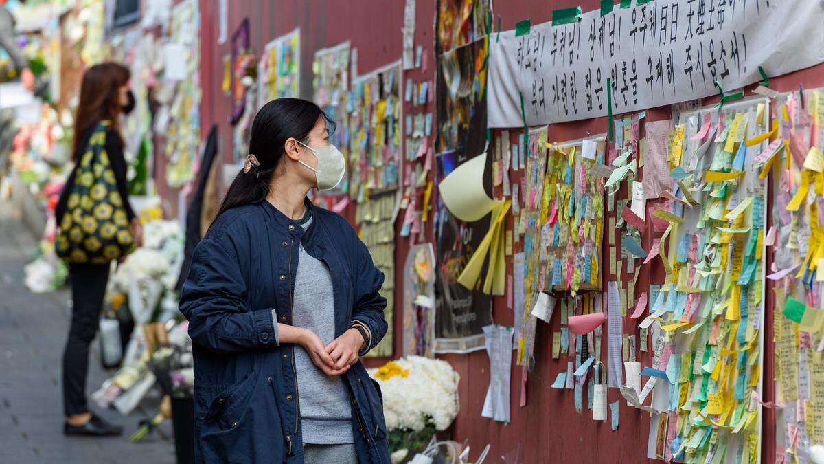    Девушка стоит у стены, на которой множество стикеров:KIM Jae-Hwan / SOPA Images / LightRocket / Getty Images