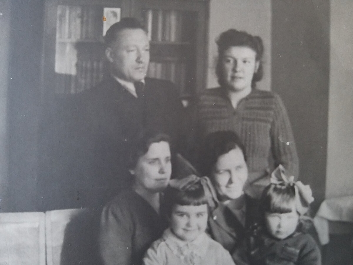 1945 г. Конец войны. Мы в квартире Ивановых на Малой Бронной. Стоят  Петр Иванович и Тамара, за спиной ПИ силуэт Сталина. За работу во время войны он был награжден орденом Отечественной войны 2 степени, орденом Красной Звезды, орденом Знак почета и медалями. Тамара поступила в 1944 г. в Финансовый институт.  Мы с сестрой Наташенькой, которой два года, сидим на коленях наших мам. 