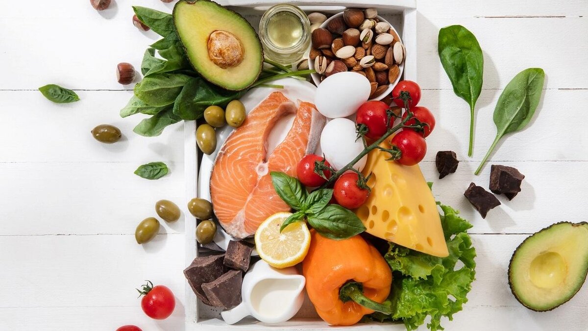    Ketogenic low carbs diet - food selection on white wooden background. Balanced healthy organic ingredients of high content of fats. Nutrition for the heart and blood vessels. Meat, fish and vegetables.