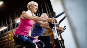    Happy mature people doing indoor biking in a fitness club Анита Ким