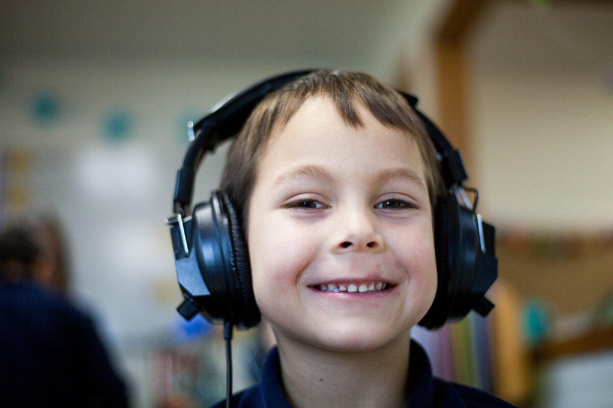 Включи подкаст для детей. Child wearing Headset Listening to Music.