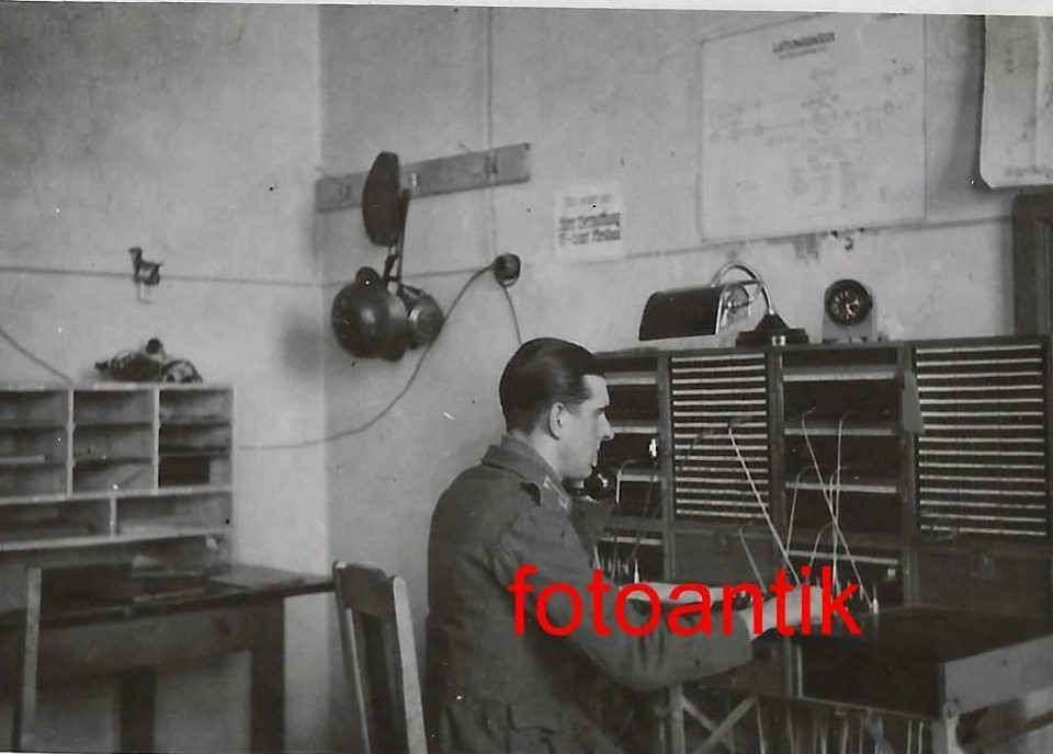 Коммутатор. Рабочее место телефониста. Примечательна схема телефонной связи, но что-то разобрать там не получится. На крючке пилотка, каска и противогаз.