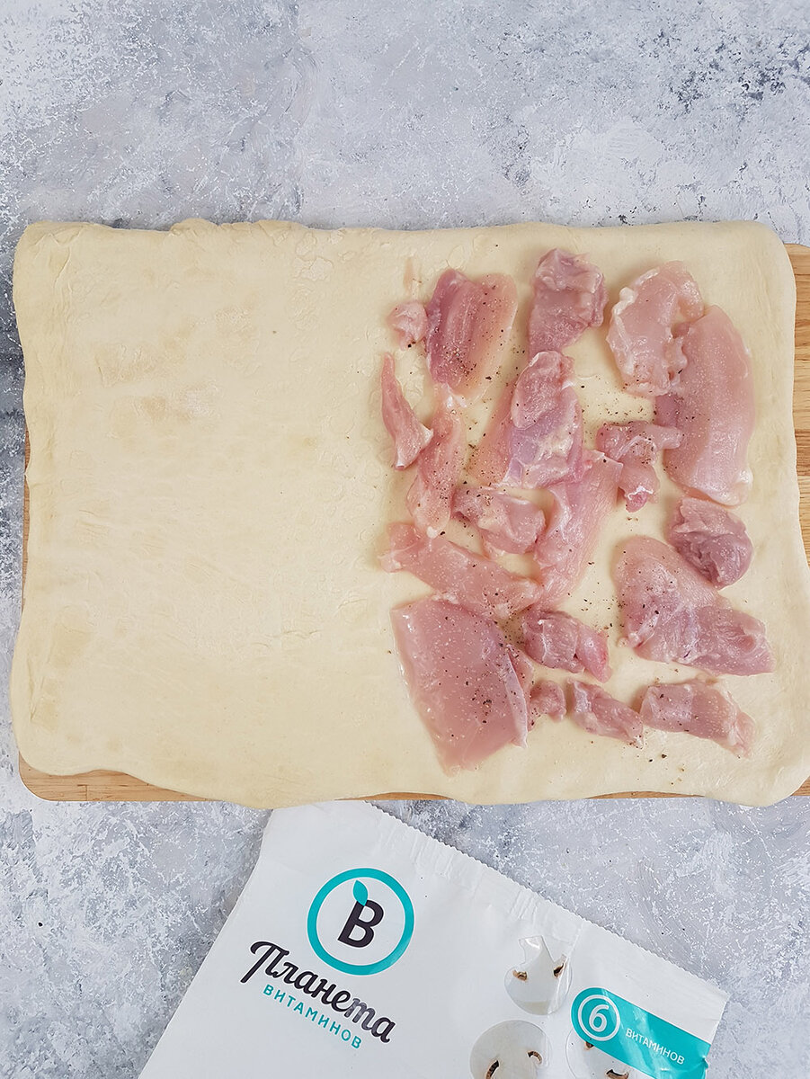 2. Размороженное тесто раскатали, на него первым слоем выложили куриное филе, посолили, добавили смесь перцев из мельницы