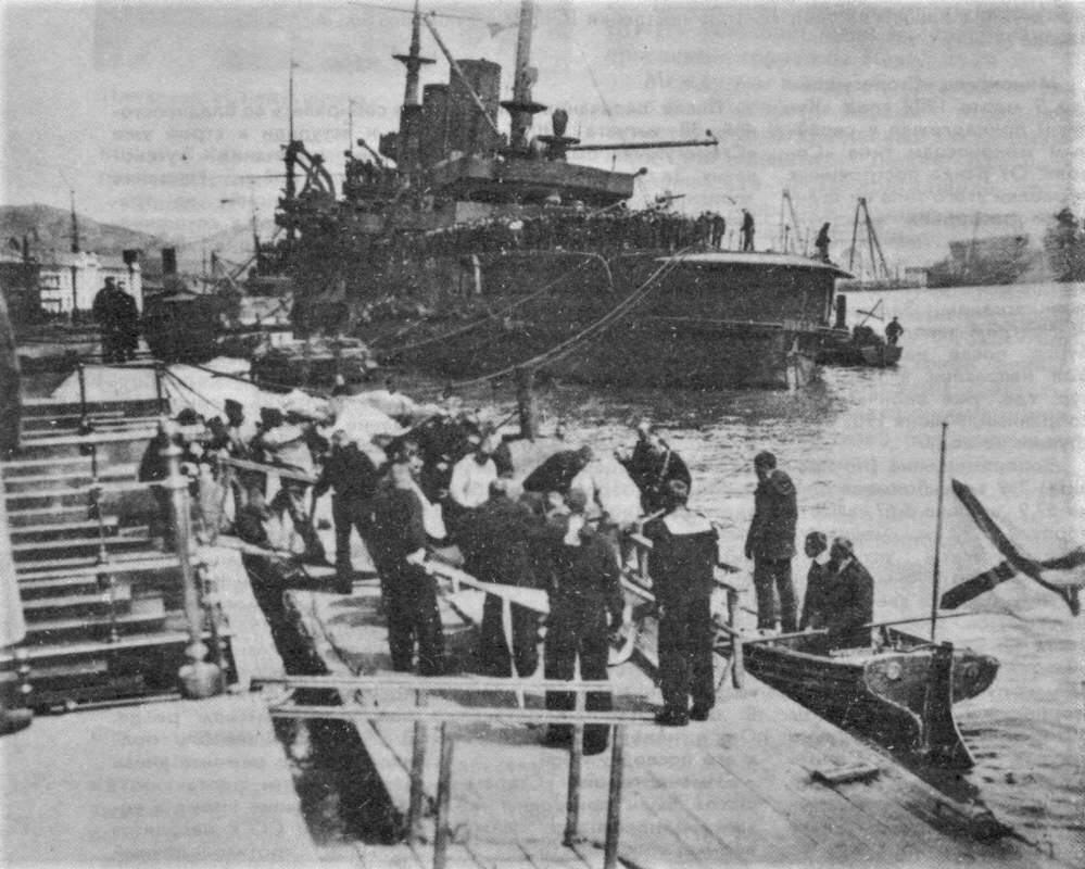 Порт-артурцы принимают со шлюпки тела погибших на "Петропавловске" боевых товарищей. На втором плане — поврежденный эскадренный броненосец "Победа"