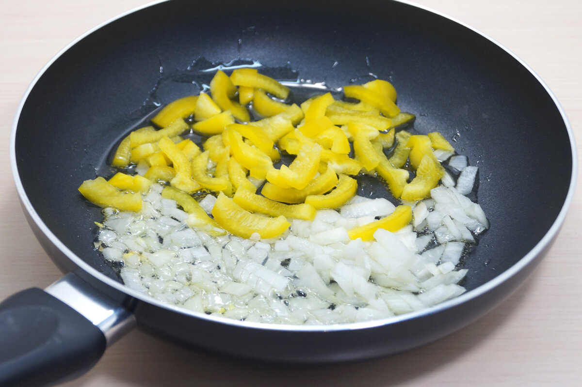 Нарезать соломкой болгарский перец, луковицу мелко нашинковать. Обжарить овощи на среднем огне 2-3 минуты до мягкости, помешивая.