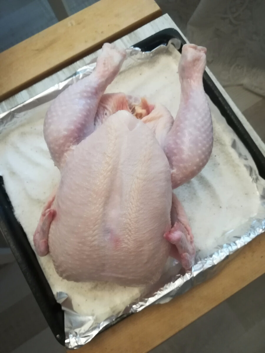 Противень застилаем фольгой, насыпаем крупную соль, выкладываем курицу, отправляем в духовку.