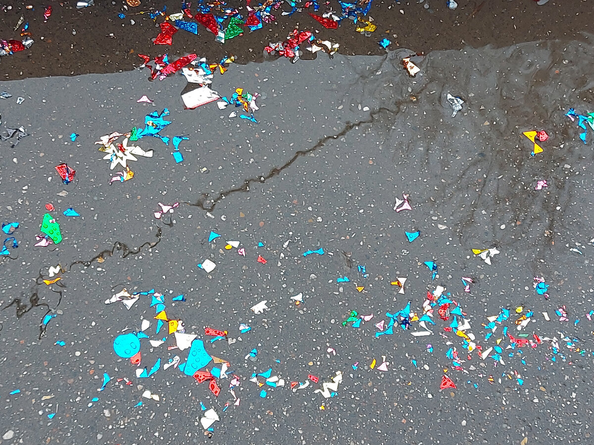 На фотке - символичное 1 января 2023 года: блестяшки от петард в асфальтовой луже.