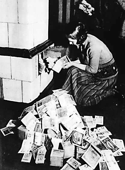 Женщина растапливает печь денежными средствами, начало 1920х. Источник цитирования фото: https://www.businessinsider.com/weimar-germany-hyperinflation-explained-2013-9#by-september-1920-prices-were-12-times-as-high-as-they-had-been-before-the-war-6, Matthew Boesler.