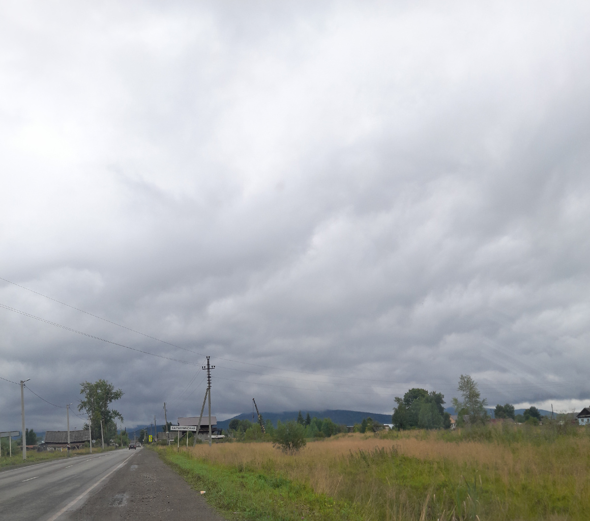 Въезд в поселок. Синяя гора в туманном облаке.