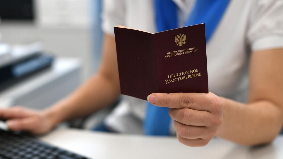    Сотрудник пенсионного фонда держит в руках пенсионное удостоверение© РИА Новости / Максим Блинов