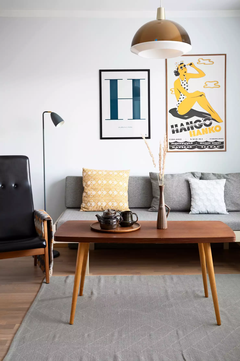 Единственная комната служит одновременно и гостиной, и спальней. На фото выше — зона отдыха и приема гостей. Основная цветовая гамма интерьера — сочетание дерева со светло-серым и тепло-желтым