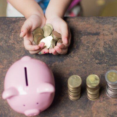    cute little girl holding coin of money and put in pink piggy bank with blur background. subject is blurred. Валерий