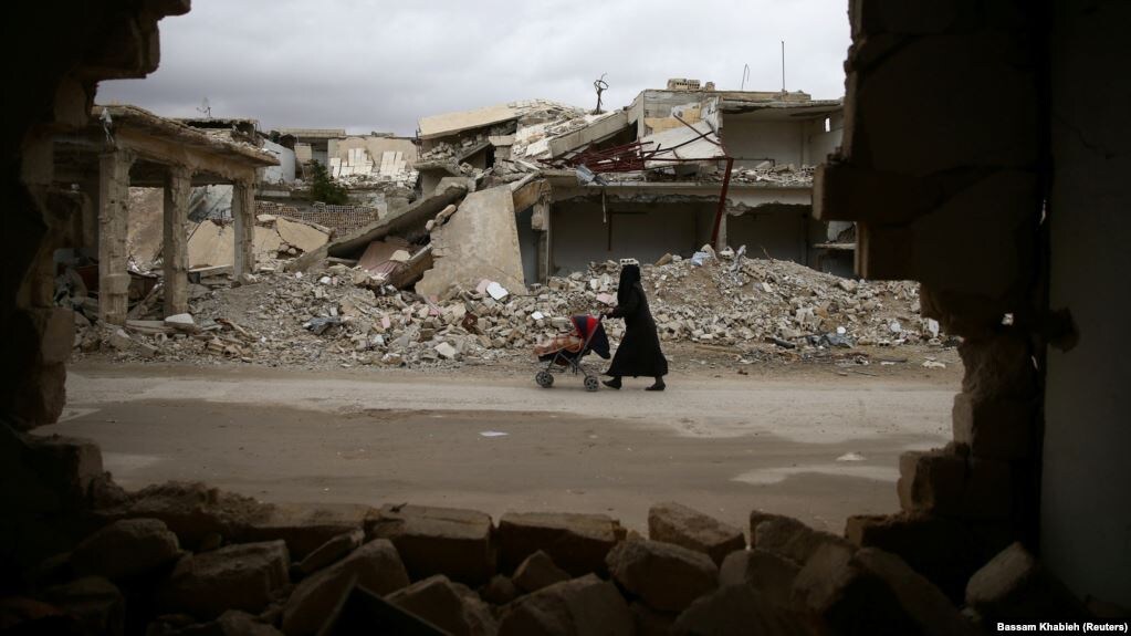 Женщина с ребенком среди руин в сирийском городе.