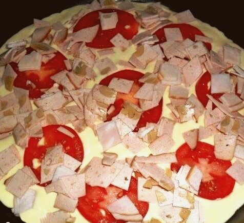 Получившуюся смесь выливаем на сковороду, смазанную растительным маслом. Сверху раскладываем начинку - у меня это колбаса и помидоры, но вы можете добавлять то, что вам больше нравится.