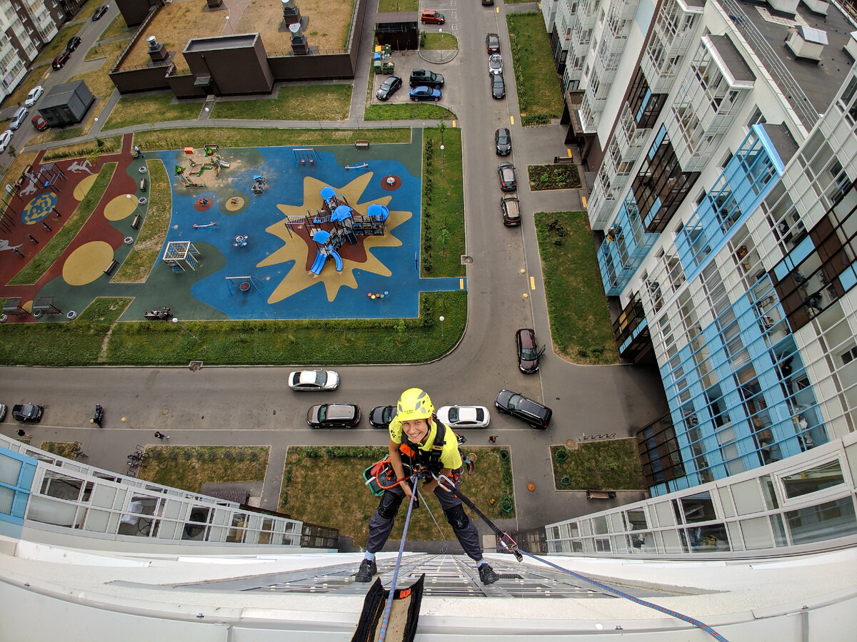 Девушка-альпинист компании Высшая лига проводит работы по сезонному мытью остекления в ЖК Чистое небо, СПб