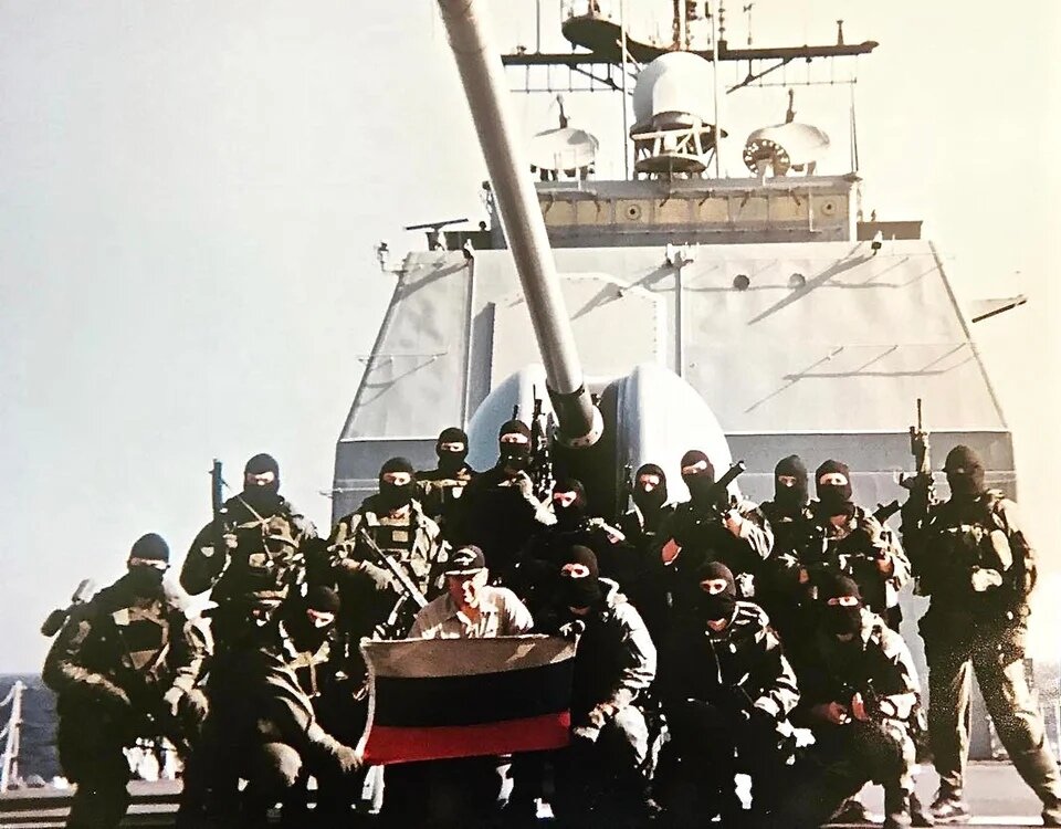 Операторы 2ой группы US Navy SEAL позируют с захваченным российским флагом на борту ракетного крейсера USS Monterey