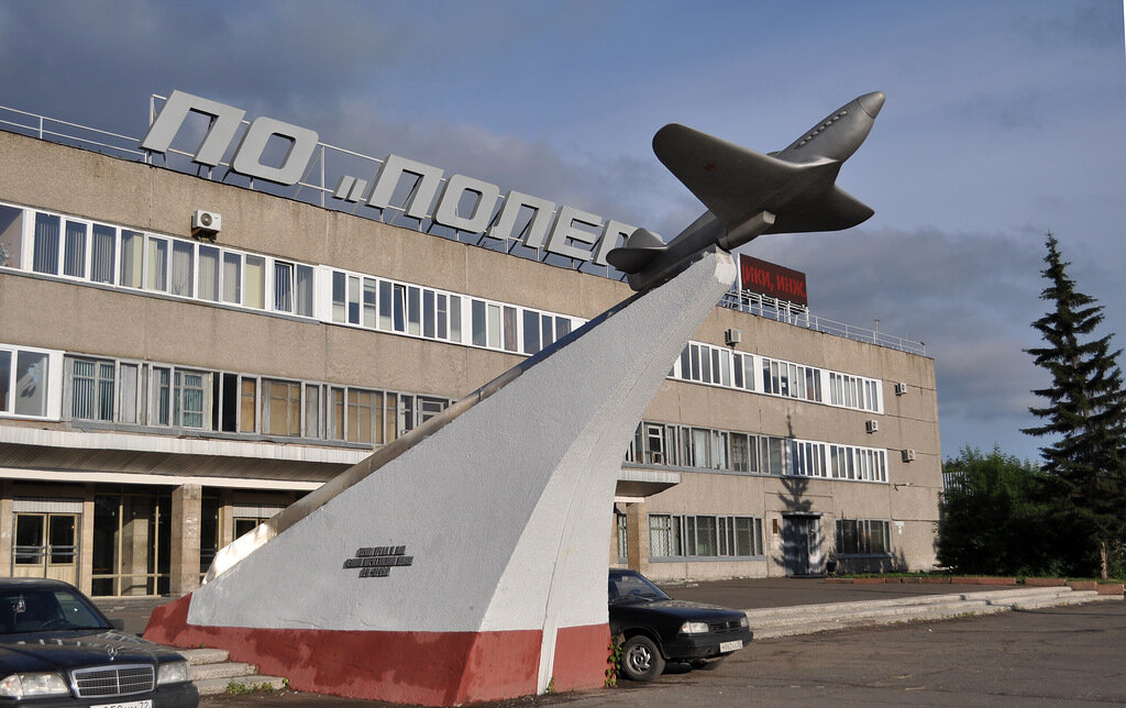 Немногие помнят, когда появился Як-9 у заводских проходных. Ветераны завода И.Т. Сурков, В.М. Ступичев уверены: памятник открыли в 1966-м, в год 25-летия завода. По другим данным он установлен в 1968-м вслед за сооружением новых проходных завода и отреставрирован к празднованию 60-летия Победы в 1985-м. В справке, представленной в музее Трудовой славы «Полета», говорится, что автором памятника является В.М. Марченко. Далее читаем: «Самолет изготовлен алюминиевым литьем с последующим уплотнением поверхности методом чеканки. Верхнюю и лицевую кромки пьедестала дополняют обрамления из листовой и трубчатой нержавеющей стали. Высота памятника – 6,5 метра. На его боковых сторонах расположены надписи, изготовленные алюминиевым литьем: «Героям труда в дни Великой Отечественной войны 1941–1945гг.».

