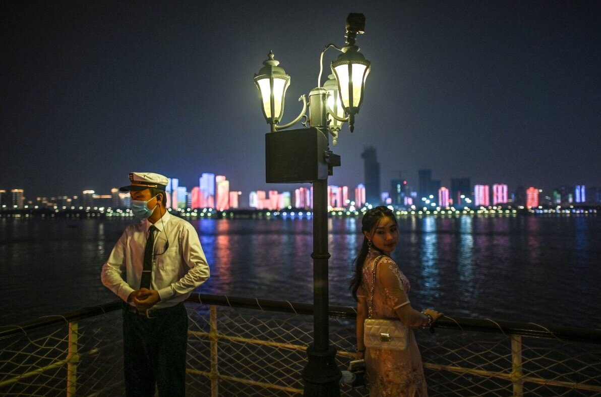 Ухань, Китай | Пассажир позирует для фотографии, пока рядом на лодке стоит охранник.