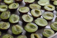 Сперва нужно тщательно промыть и просушить свежие сливы. Нарезать плоды на половинки и выложить на широкий противень с антипригарным покрытием.