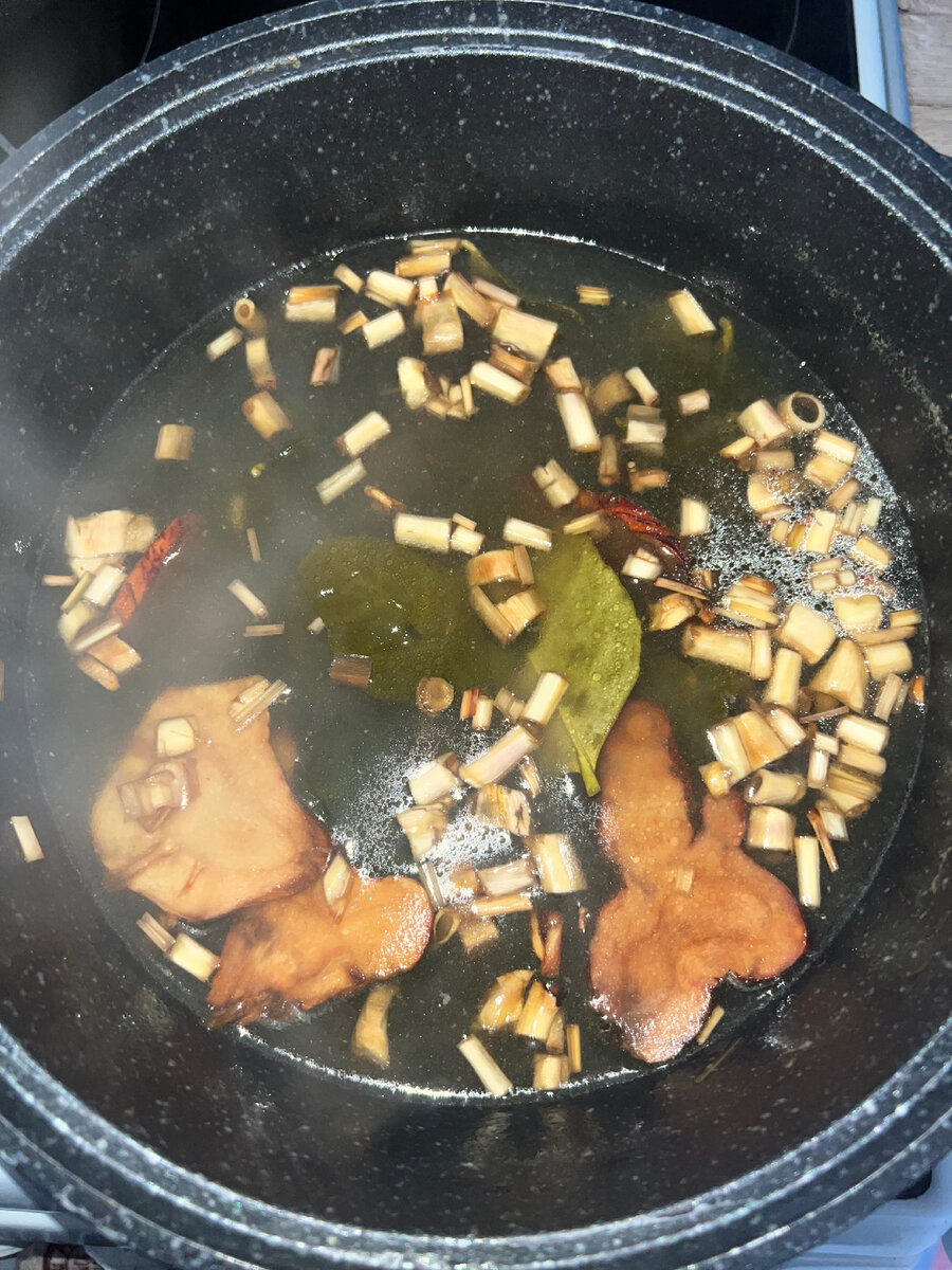 Добавьте в бульон листья каффирского лайма, лемонграсс и корень галангала, доводим до кипения, сбавляем огонь, варим 30 минут.