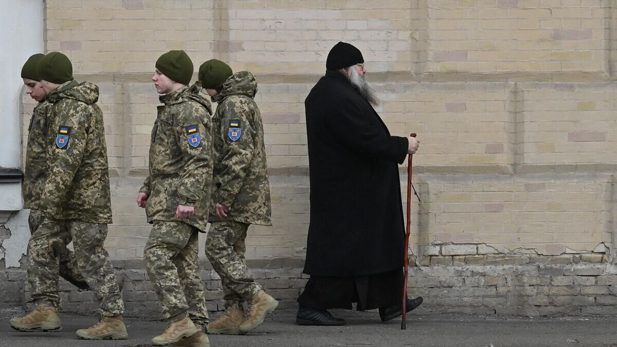 Украинские военнослужащие проходят мимо монаха в Киево-Печерской Лавре. 14 марта 2023 года © AFP 2023 / Sergei Supinsky