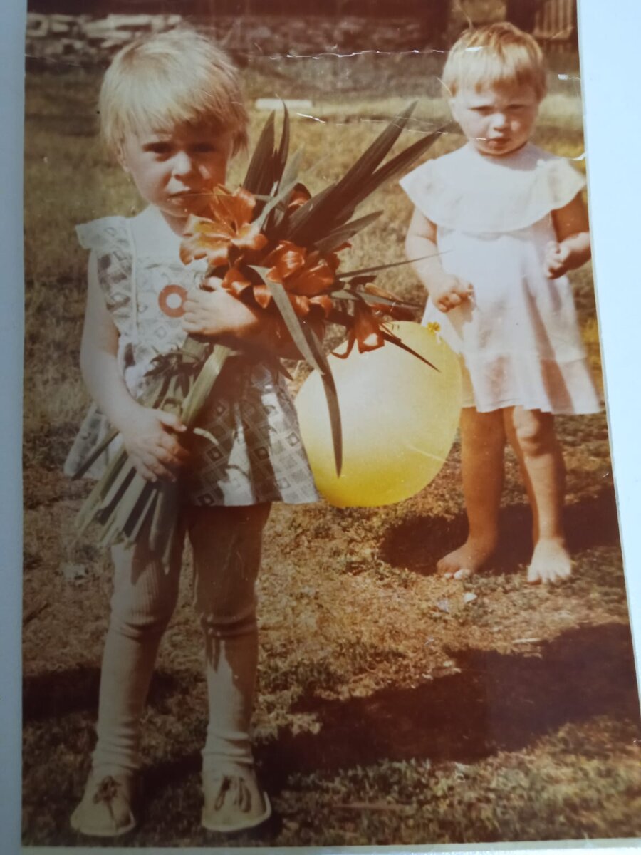 Я во дворе садика с тигровыми лилиями. Это лето, выпускной. Моя подруга Наташа с желтым шаром.