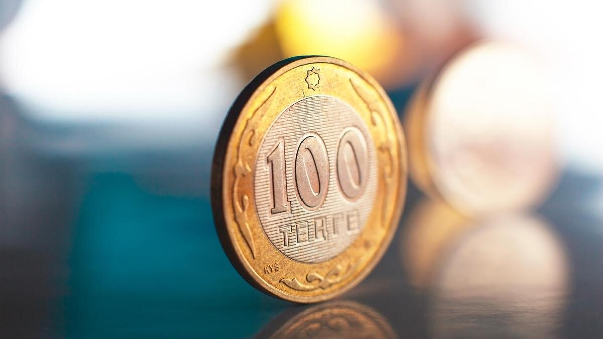    Монета тенге стоит ребром на столе:freedarst/Getty Images