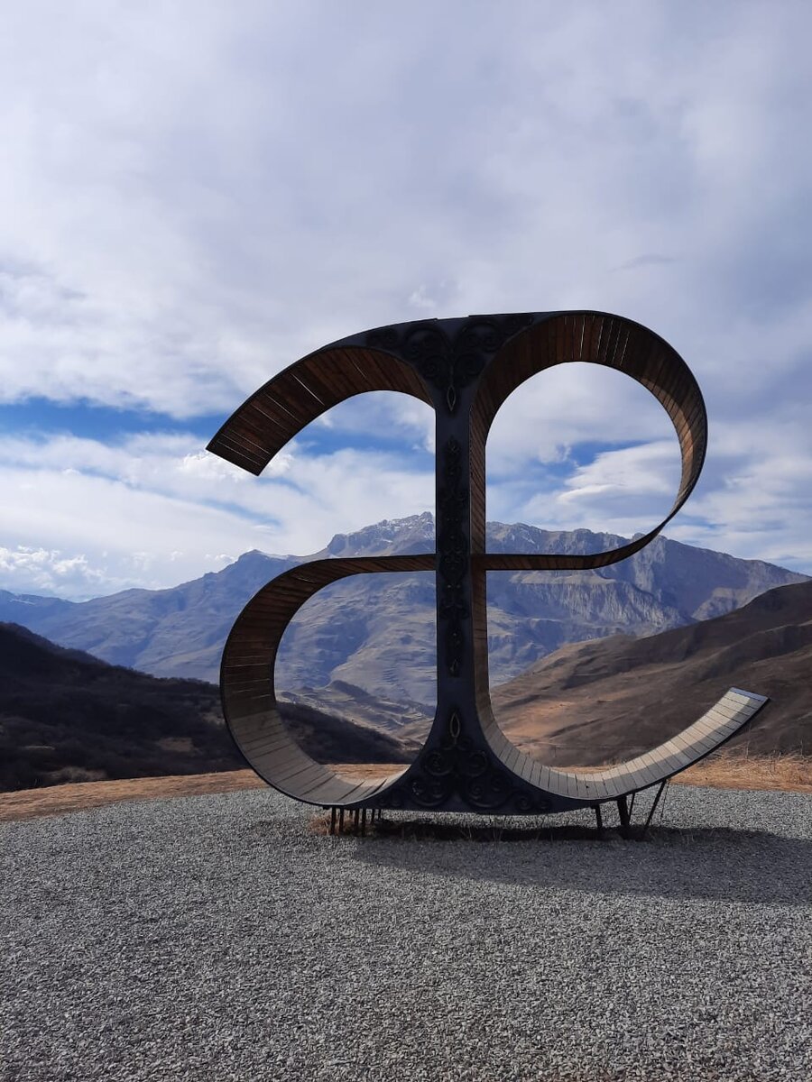 Буква — символ осетинского языка, выполненная из дерева и металла. Установлена где-то между Даргавсом и Фиагдоном
