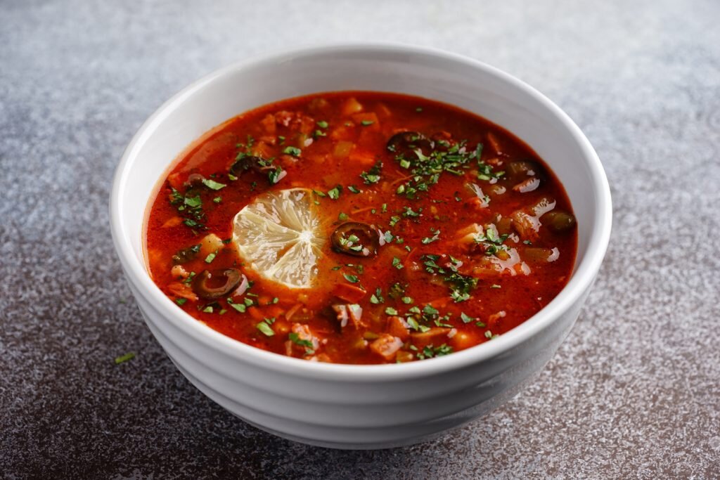 Ингредиенты: ● Сосиски — 2 шт.
● Лук — 1 шт.
● Морковь — 2 шт.
● Картофель -2 шт.
● Огурцы корнишоны — 5 шт.
● Оливки — 1 банка
● Лимон — 4 кружочка
● Подсолнечное масло
● Томатная паста — 2 ст. ложки
Приготовление:В кастрюлю налить воды, довести до кипения. Картофель очистить, нарезать кубиками, бросить в кипящую воду.
Сосиски нарезать кружочками. Обжарить на растительном масле. Затем обжаренные кружочки сосисок переложить в кастрюлю с картофелем.
Морковь натереть на тёрке. Лук нарезать кубиками среднего размера. Выложить в сковороду с растительным маслом. Лук и морковь обжарить 10 минут. Затем к овощам добавить томатную пасту. Тушить вместе с томатной пастой 5-10 минут.
Нарезать корнишоны, оливки на кружочки. Кружочки лимона на четвертинки.
Обжаренные лук и морковь, нарезанные огурцы, оливки, дольки лимона добавить в кастрюлю с сосисками и картофелем. Все вместе варить 10-15 минут. 
 Желаю Вам Bon Appetit или Приятного аппетита. Новые рецепты вкусных и необычных блюд ждут вас каждый день. ПОДПИСЫВАЙТЕСЬ НА МОЙ КАНАЛ СТАВЬТЕ ЛАЙК ЕСЛИ ВАМ ПОНРАВИЛОСЬ ЭТО БЛЮДО.