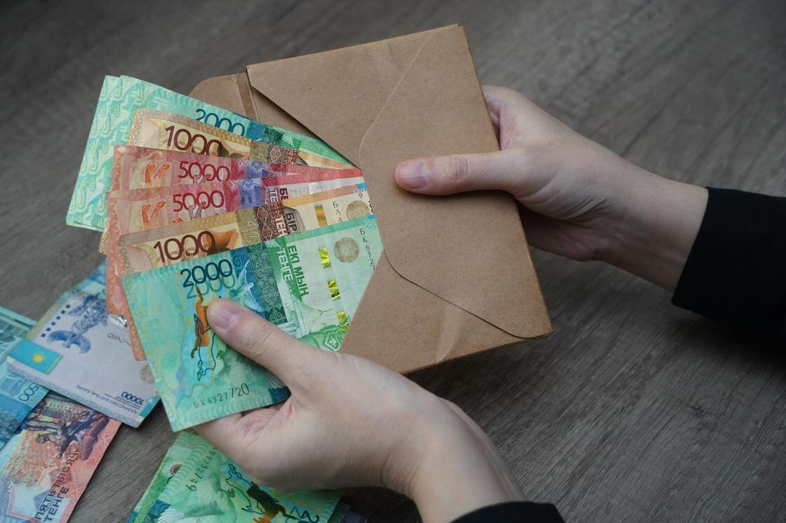    Женщина достает из конверта деньги:NUR.KZ/Владимир Третьяков