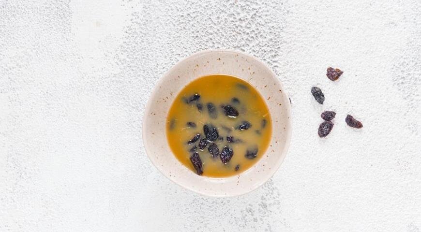 Приготовьте тесто для кулича. Прежде всего, тщательно вымойте изюм и переложите в мисочку. Залейте соком и прикройте салфеткой. Оставьте на 1 ч при комнатной температуре