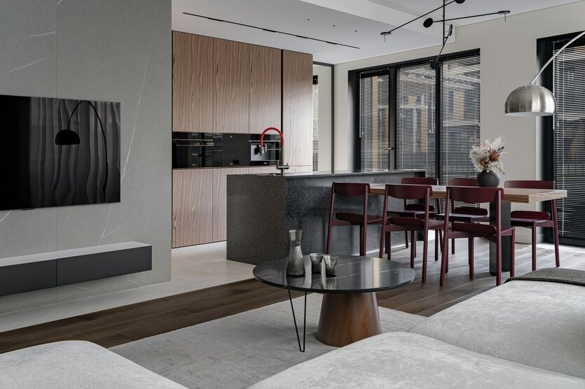 Стены ТВ-зоны облицованы керлитом с текстурой натурального гранита от компании Laminam. Контрастный стык паркета и микробетона на полу делит квартиру пополам и вторит коробам на потолке, в которых спрятаны все инженерные коммуникации.