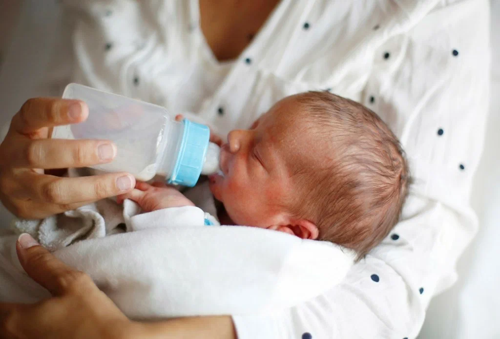 Искусственное вскармливание новорожденного. Кормление из бутылочки новорожденного. Бутылочка для кормления. Докорм малыша.
