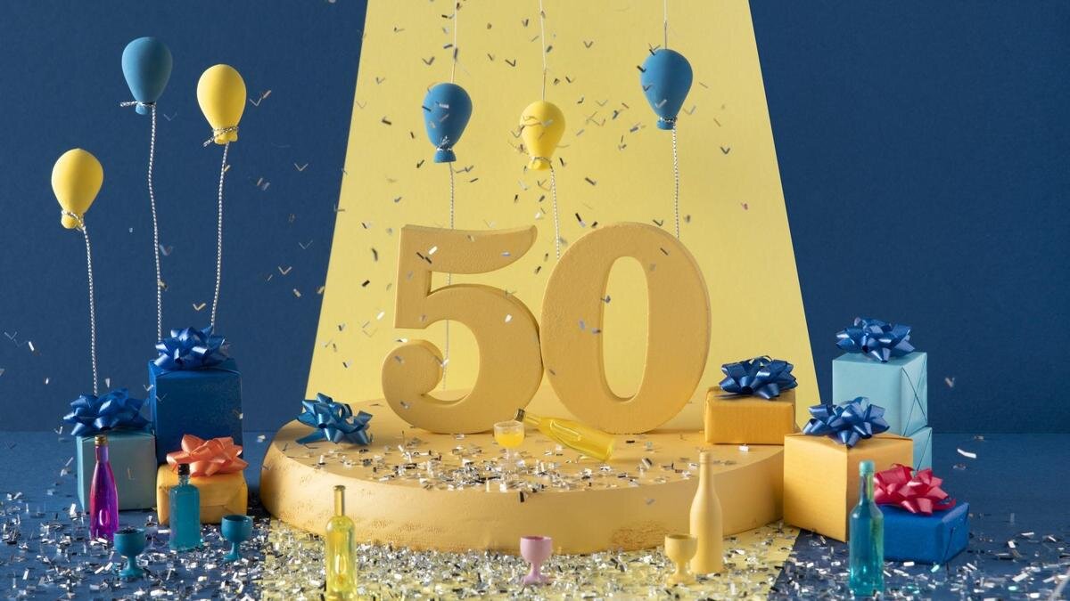    Инсталляция с большой цифрой 50 на золотом подиуме. В коробках упакованы подарки, украшенные шариками, цветными бутылками, рассыпанным конфетти:Freepik