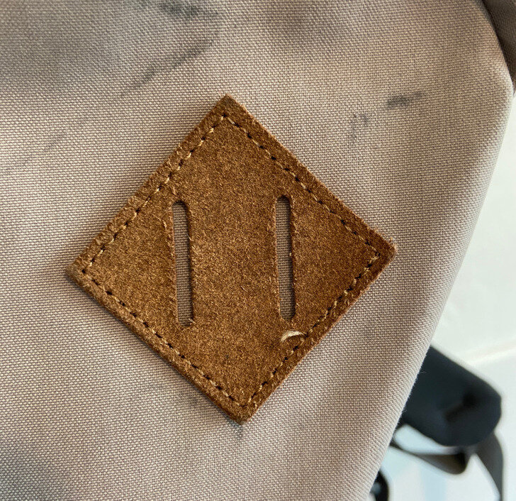 Любопытно, что эта нашивка, похожая на пятачок, нужна не только для красоты — у нее есть конкретная функция. Через ее прорези можно продеть веревку и что-нибудь повесить. Например, если в походе вам понадобится вторая пара обуви, но она не будет помещаться в рюкзак, вы можете повесить ее за шнурки, используя эту ромбовидную нашивку. И хотя изначально ее придумали для туристических рюкзаков, теперь она стала неотъемлемой частью дизайна и многих повседневных рюкзаков тоже.