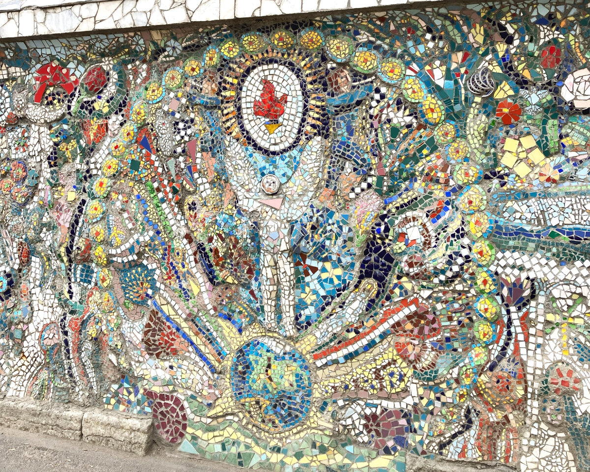 Стена жилого дома в мозаичном дворике Владимира Лубенко: человек на земном шаре поднял руки-крылья к пылающему огню.