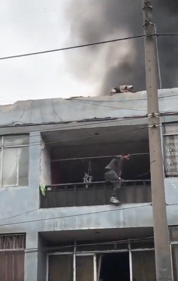 Ариас взбирается наверх. Источник фото: https://www.reshareworthy.com/man-rescues-dogs-trapped-on-roof-of-burning-building-peru/