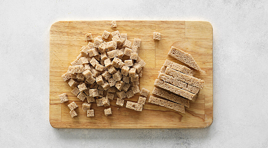 1. Подготовьте ингредиенты салата Цезарь. С хлеба срежьте корку, мякиш нарежьте кубиками. Выложите на сухую сковороду и, помешивая, жарьте на слабом огне до состояния сухариков. Дайте остыть.