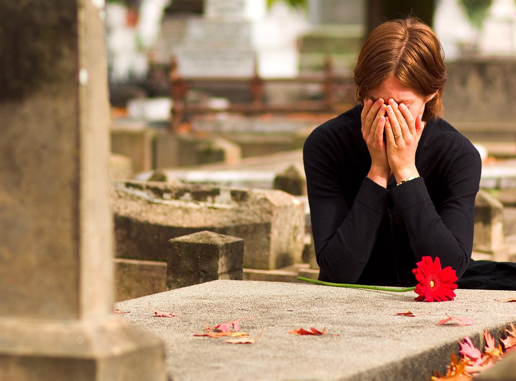 Девушка плачет на кладбище. Женщина грустит.