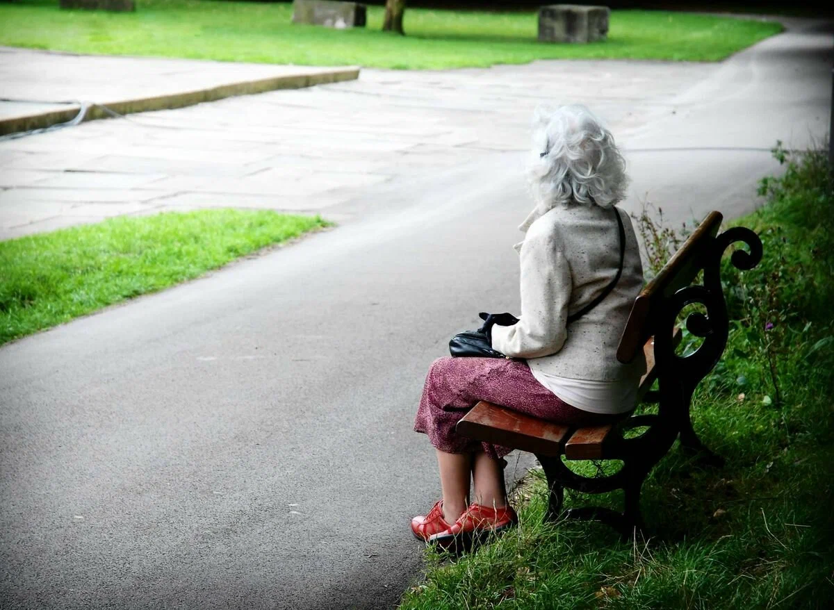 Впереди всех быстро шел небольшой сухонький старичок. Пожилая женщина на скамейке в парке. Бабушка на скамейке в парке. Бабушка спиной на скамейке. Одиночество пожилых.