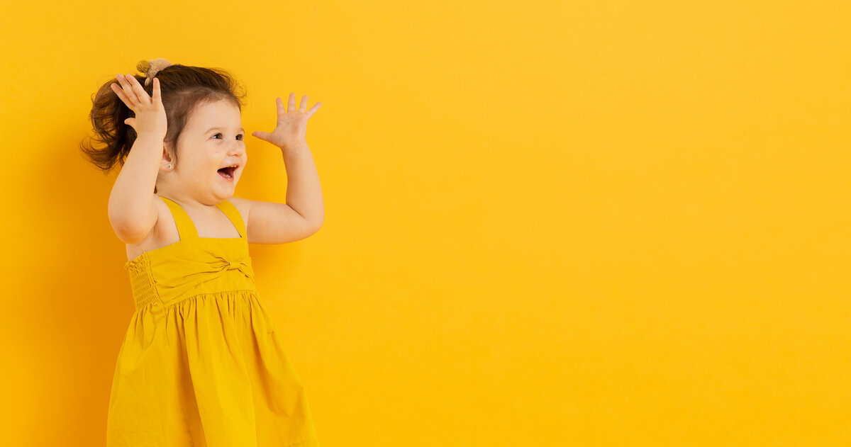 Baby and yellow. Счастливая девочка на белом фоне. Радостные дети на черном фоне. Радостный ребенок на однородном фоне. Логотип Kids Style.