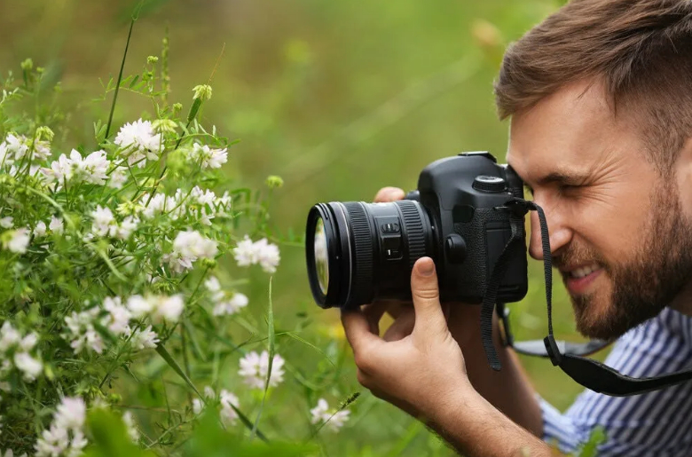 Фотографирует цветы на телефон