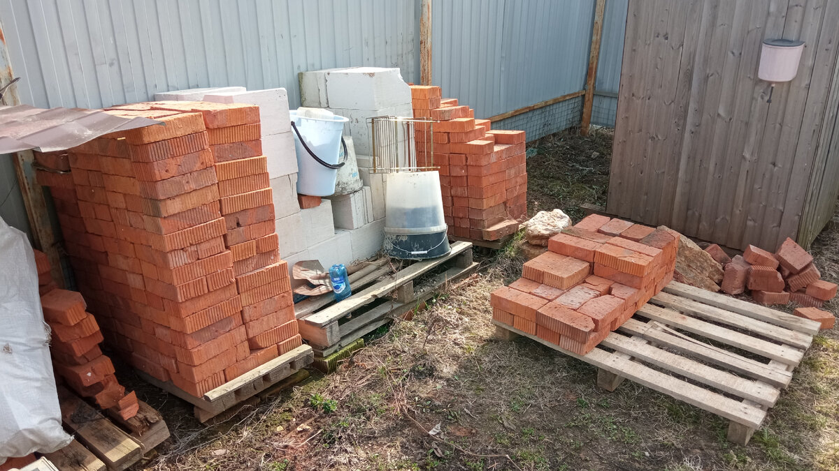 Кирпичи возле забора.