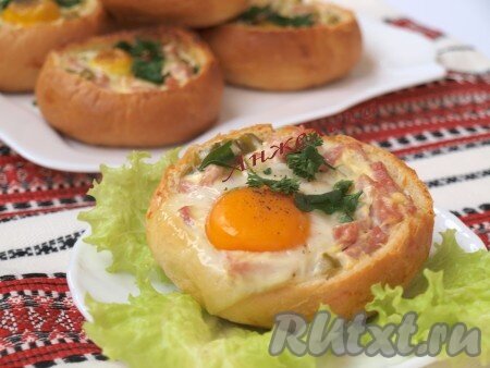 У каждой булочки нужно срезать верх и аккуратно вынуть мякиш.Нарезать соломкой ветчину и огурцы. Затем смешать их с майонезом и горчицей.Каждую булочку изнутри смочить половиной столовой ложки молока и смазать  сливочным маслом. Добавить начинку из ветчины и огурца, посыпать порезанной зеленью. В каждую булочку вбить по яйцу (если Вы будете готовить с куриными яйцами, то берите не крупные). Желтки посыпать солью и перцем. Закусочные булочки с ветчиной, огурцом и яйцом запечь в разогретой духовке при температуре 200 градусов до загустения яичного белка. Получается очень вкусно и сытно!