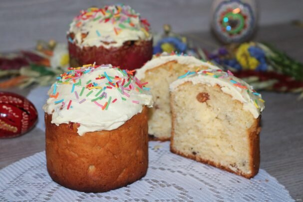 Ингредиенты: Мука  — 300 Грамм 
Молоко  — 125 мл.
Дрожжи  — 20 гр 
Сахар  — 5 ст. ложек 
Масло сливочное  — 150 гр
Изюм  — 50 гр 
Цукаты  — 50 гр 
Яйцо куриное  — 2 шт 
Соль  — 1 щепотка 
Сахарная пудра  — 2 ч. ложки (для глазури) 
Сухое молоко  — 60 гр (для глазури) 
Вода  — 25 мл (тёплая, для глазури) 