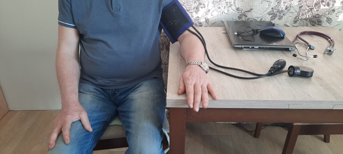 Рука, на которую одета манжета лежит на столе 
