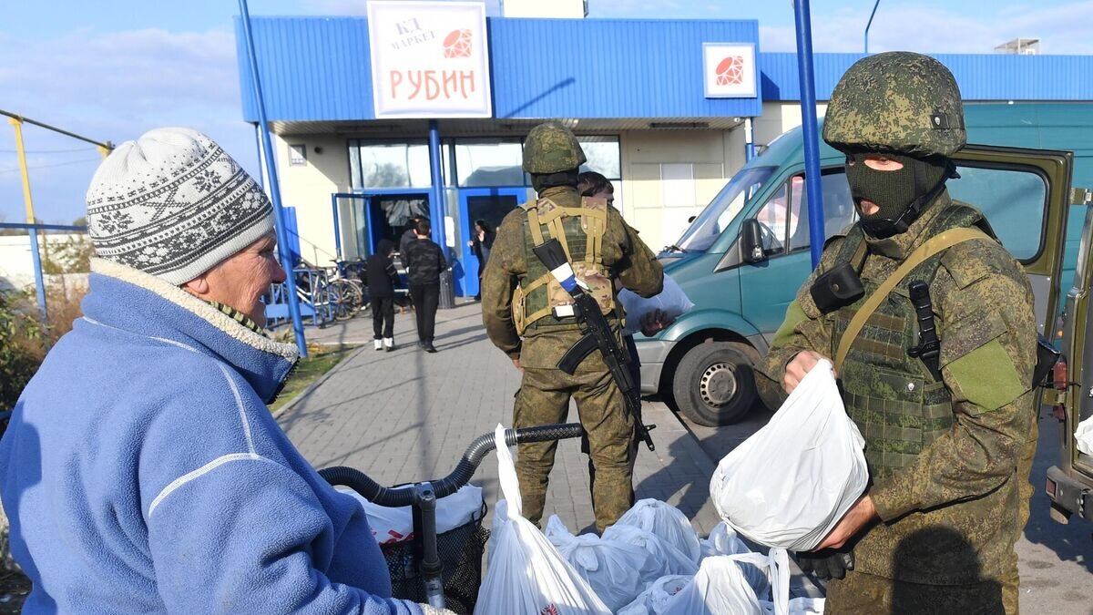    Мобилизованный военнослужащий РФ передает гуманитарную помощь местной женщине в городе Каменке-Днепровской Запорожской области© РИА Новости / РИА Новости